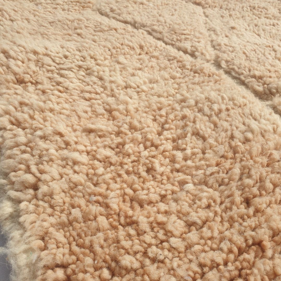 Close-up of a Wynona beige Beni Ourain accent rug showing the soft natural wool pile with the carved diamond and rectangular relief pattern visible only through subtle pile height variation, a tone-on-tone composition handwoven in 100% natural wool
