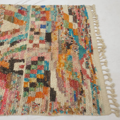 Detail shot of the checkerboard band and diamond motif on Yaftna Moroccan rug - the bold multicolor squares interrupting the confetti field, with an X-shaped figure and zigzag chevron visible nearby