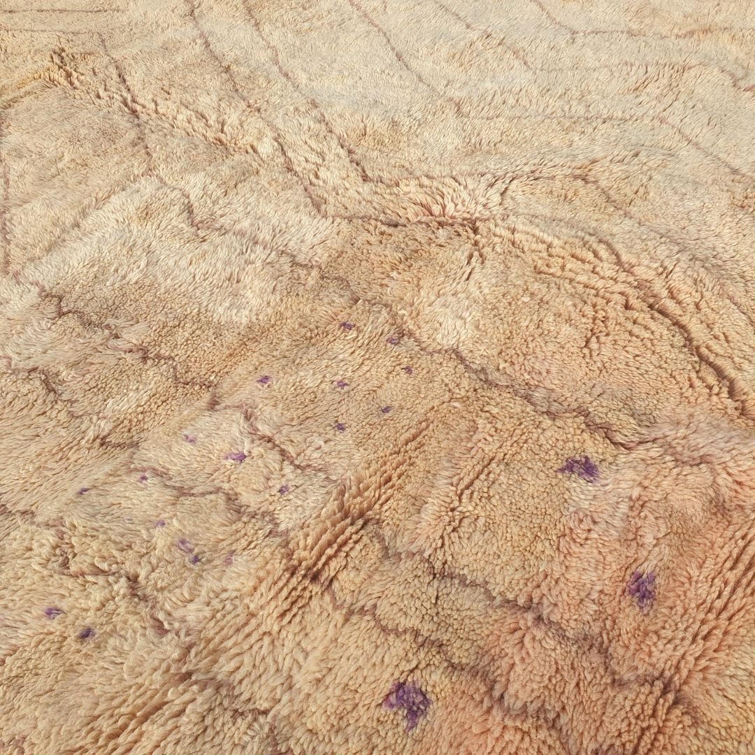 Detailed view of subtle purple accents and yellow geometric motifs against the pale nude pink and beige background of this fluffy Berber shag rug