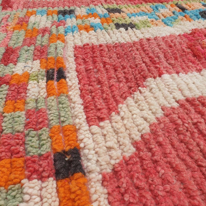 Close-up of a handwoven Boujad Berber rug showing intricate multicolor geometric details – rich red wool pile with patches of turquoise, green, orange, and cream in an abstract expressionist pattern