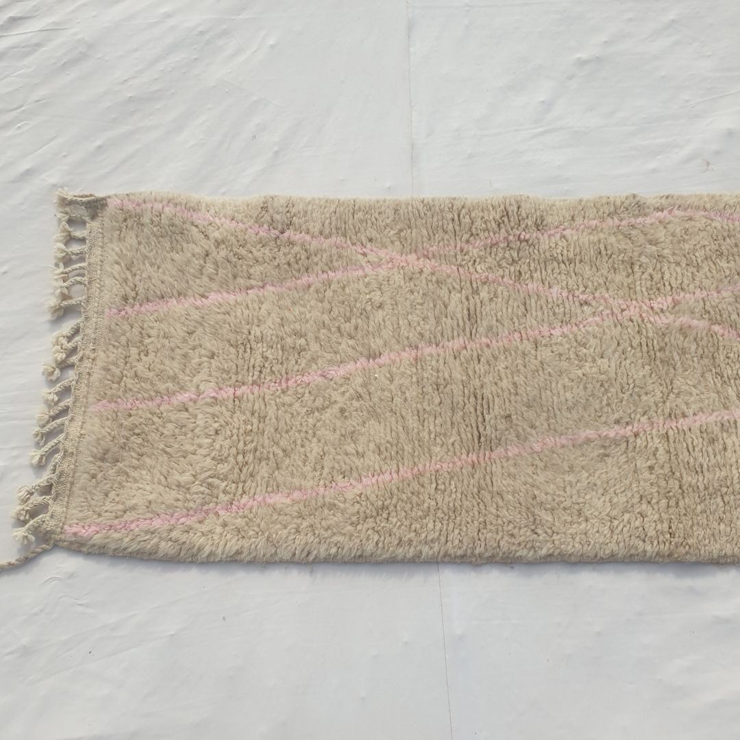 Detail shot of the sparse pink diagonal line composition on Cotya ivory Beni Ourain runner - delicate crossing lines in dusty pink against the dominant ivory wool field, a minimalist gesture of colour rather than a saturated pattern