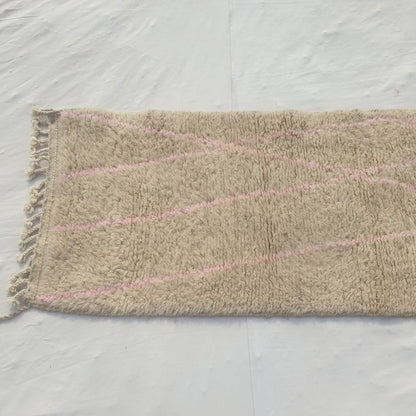 Detail shot of the sparse pink diagonal line composition on Cotya ivory Beni Ourain runner - delicate crossing lines in dusty pink against the dominant ivory wool field, a minimalist gesture of colour rather than a saturated pattern