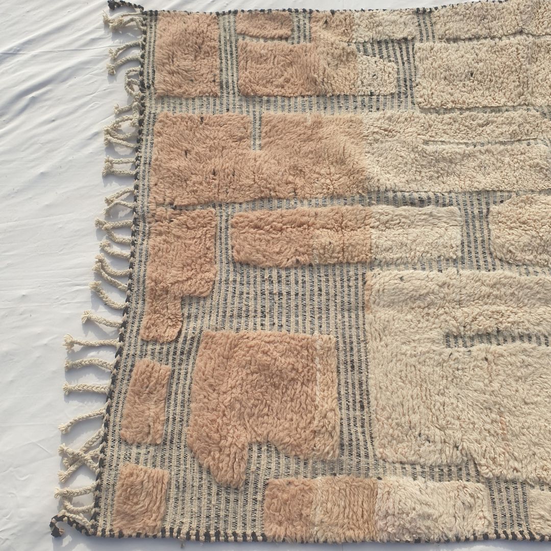 Top-down view of a Fareja Beni Ourain Moroccan patchwork rug showing the full block composition - varying-sized rectangular blush-rose and ivory wool sections arranged in an irregular organic grid pattern, with natural tasselled fringe visible at the top edge