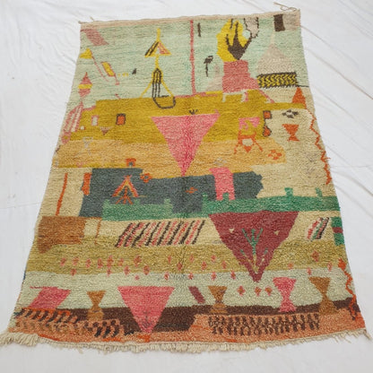 Authentic Moroccan rug 193x308 cm laid flat outdoors - mint green, mustard gold, pink and teal colour zones with a dense pictorial abstract composition and warm terracotta harlequin border, handwoven in Morocco
