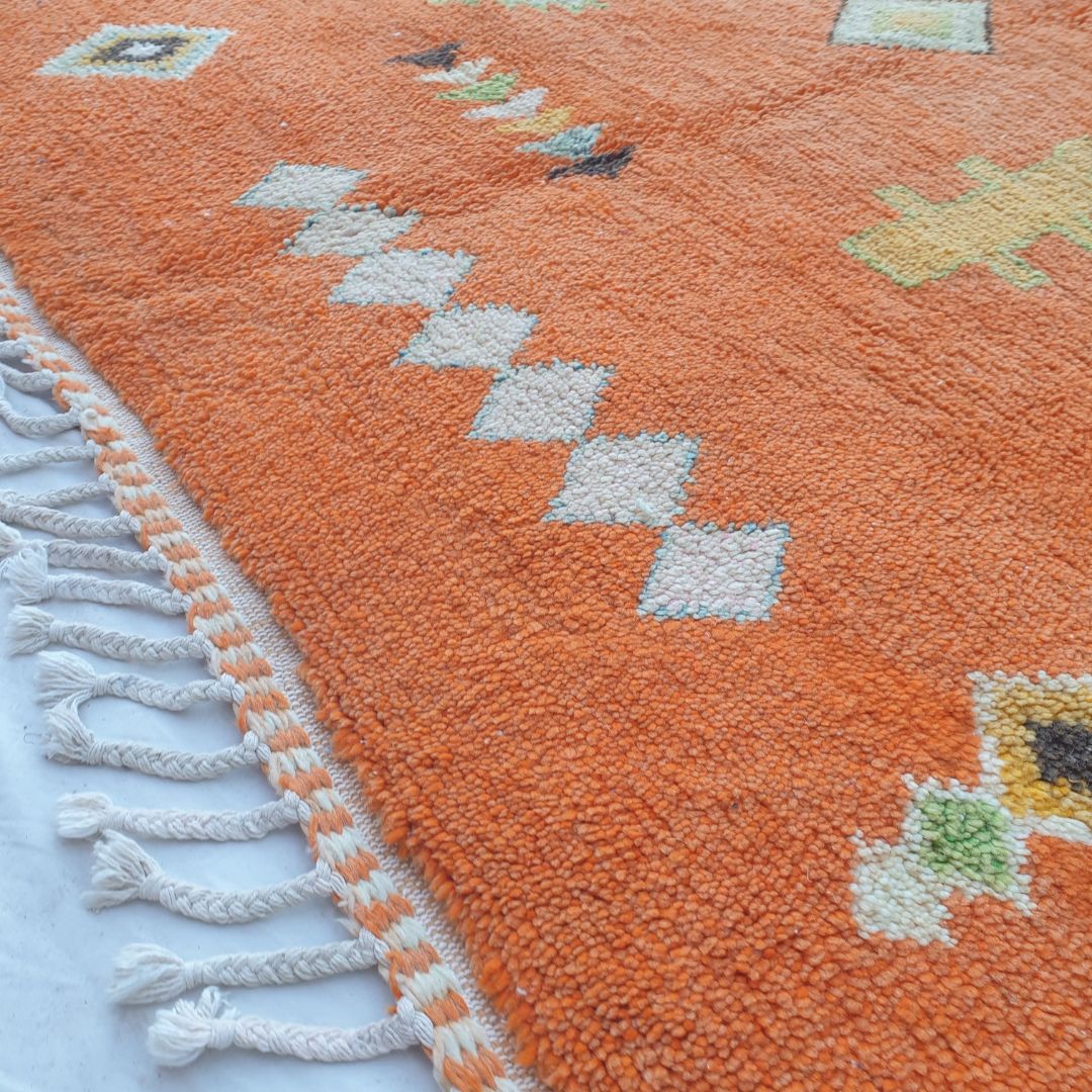 Intricate handwoven Berber symbols and colorful geometric designs on vibrant orange Boujad Moroccan wool rug, showcasing diamonds, arrows and traditional motifs