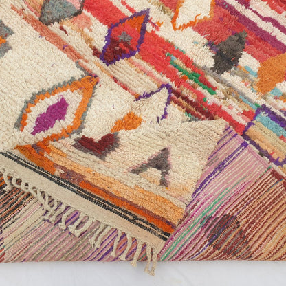 Hand-knotted fringe and detailed border in warm red tones framing the bold colorful diamond tribal design on 6x9 Boujad Moroccan rug