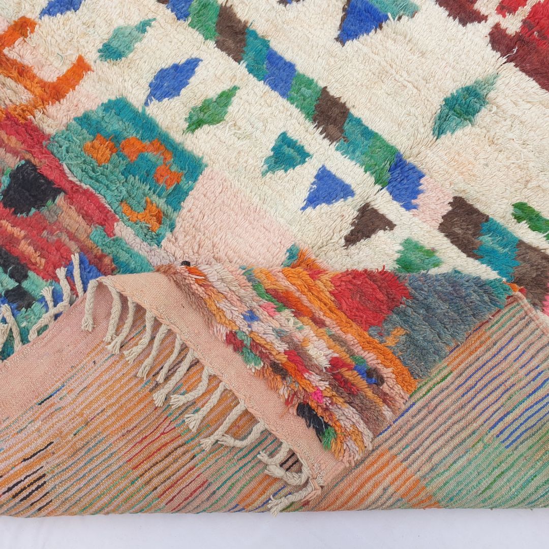Hand-knotted fringe and detailed border in warm tones framing the bold colorful geometric tribal design on 6x9 Boujad Moroccan rug