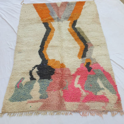 handwoven Boujad Berber rug (202x298 cm) laid flat on white, the full composition visible: ivory ground, twin orange zigzag lightning columns from the top, and bold abstract shapes in hot pink, slate blue, black and gold below.