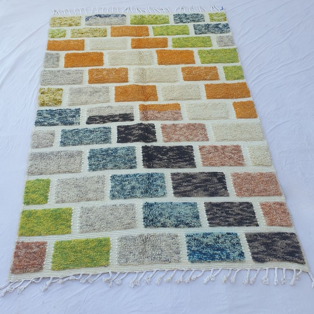 Boho living room featuring 6x10 multicolored Beni Ourain rug with geometric bricks, anchoring sofa in vibrant luxury