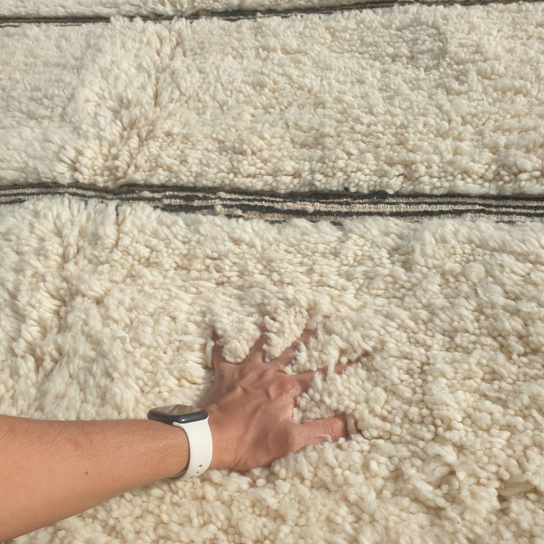 Close-up of an ivory Beni Ourain rug showing the soft natural wool pile with bold black horizontal stripe groupings - some single thin lines, some doubled or tripled together, creating a rhythmic graphic pattern, handwoven in 100% natural wool