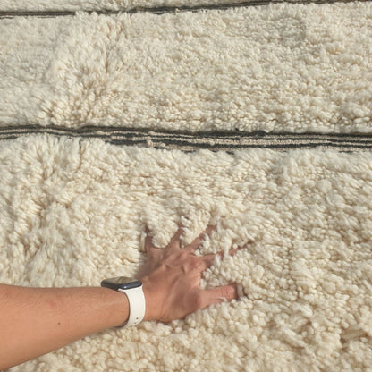 Close-up of an ivory Beni Ourain rug showing the soft natural wool pile with bold black horizontal stripe groupings - some single thin lines, some doubled or tripled together, creating a rhythmic graphic pattern, handwoven in 100% natural wool