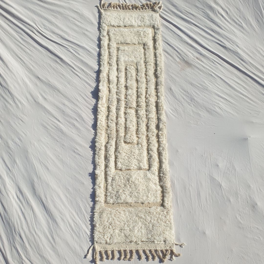 Authentic Beni Ourain Moroccan runner rug 74×290 cm laid flat — pure white natural undyed wool with a subtle tactile carved relief pattern of nested concentric rectangles, no dye, no colour, just the natural beauty of hand-knotted Atlas mountain wool, made by Beni Ourain Berber women