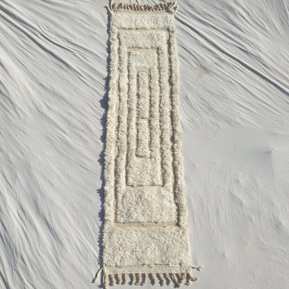 Authentic Beni Ourain Moroccan runner rug 74×290 cm laid flat — pure white natural undyed wool with a subtle tactile carved relief pattern of nested concentric rectangles, no dye, no colour, just the natural beauty of hand-knotted Atlas mountain wool, made by Beni Ourain Berber women