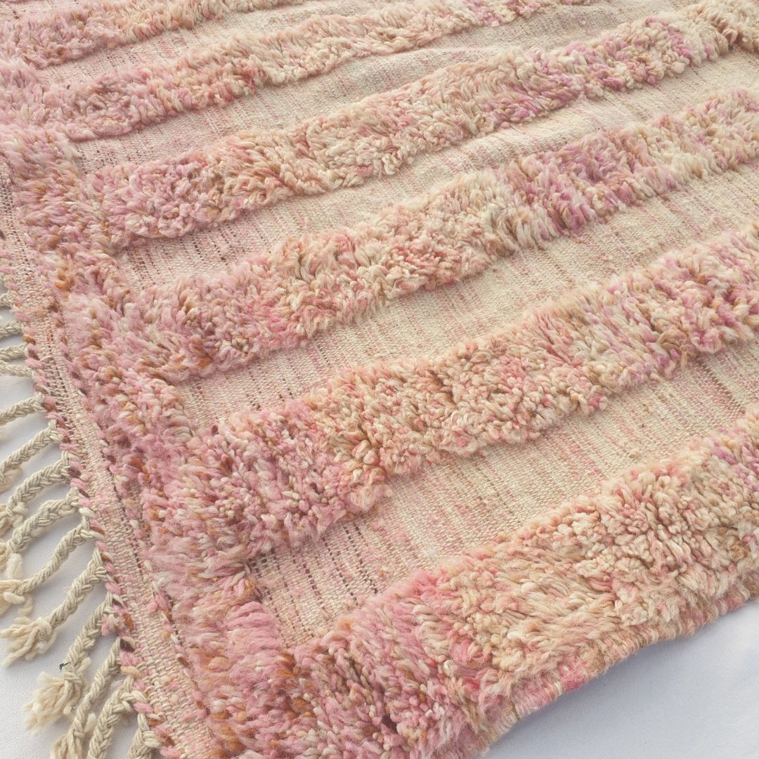 Close-up of a Nayra dusty rose Beni Ourain rug showing the soft chalky pink wool pile with a tonal geometric maze pattern - two stacked mirrored rectangular panels each with concentric rectangular U-forms creating a labyrinthine key pattern, entirely in tonal pink-on-pink, handwoven in 100% natural wool