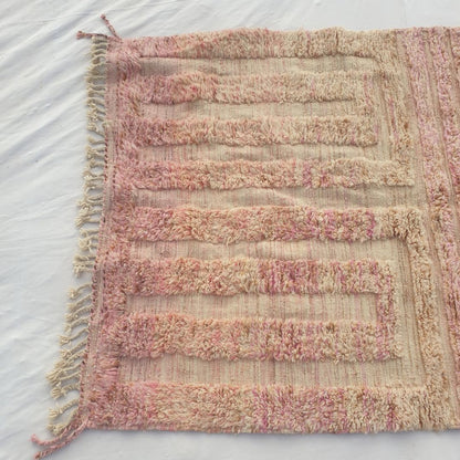 Detail shot of the geometric maze key pattern on Nayra dusty rose Beni Ourain rug - the concentric rectangular U-shapes nesting inside each other in two mirrored vertical panels, the tonal pink-on-pink composition visible in the slight sheen difference between the base and pattern wools