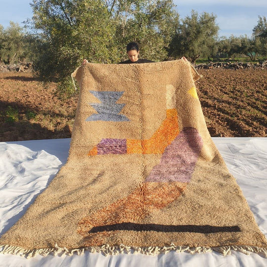 Luxury 7x10 Beni Mrirt Moroccan rug with abstract geometric patterns in blue, orange, purple on beige shag wool base held outdoors