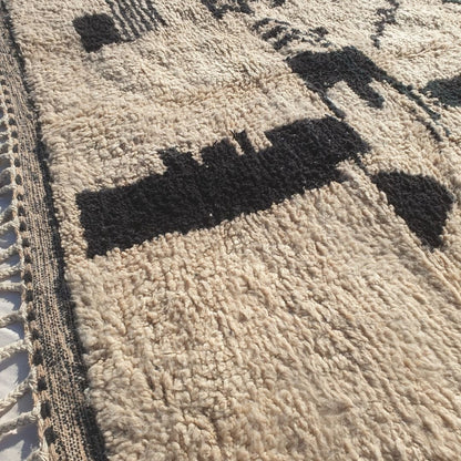 Intricate abstract tribal black shapes including rectangles, triangles, and freeform lines on authentic Beni Ourain wool rug, showcasing powerful Berber design