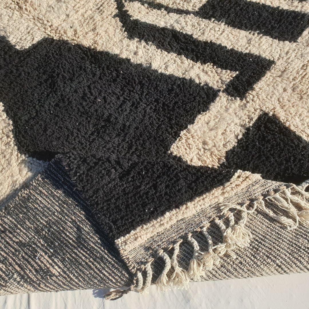 Hand-knotted fringe and detailed border framing the bold abstract tribal pattern on 7x9 Beni Ourain Moroccan rug