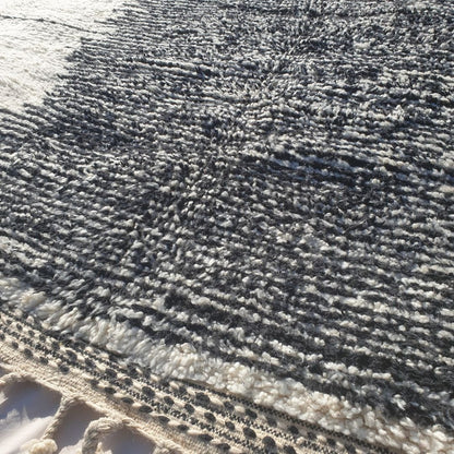 Detailed asymmetrical black geometric motifs and freeform lines on authentic Beni Ourain wool rug, showcasing traditional Berber tribal design