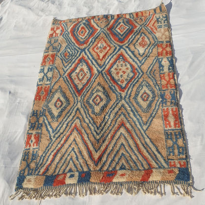 Intricate red and blue diamond accents with beige background highlighting fluffy weave of high-end Moroccan plush rug