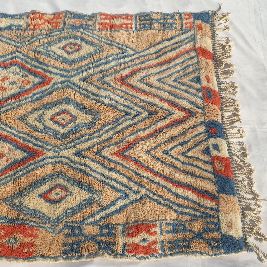 Detailed view of bold blue and red diamond geometric tribal motifs on the colorful Berber Beni Mrirt shag rug