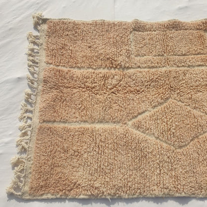 Detail shot of the carved relief motif on Wynona beige Beni Ourain accent rug - the central diamond shape and surrounding nested rectangular blocks rendered entirely through pile height, a warm tan tone-on-tone composition